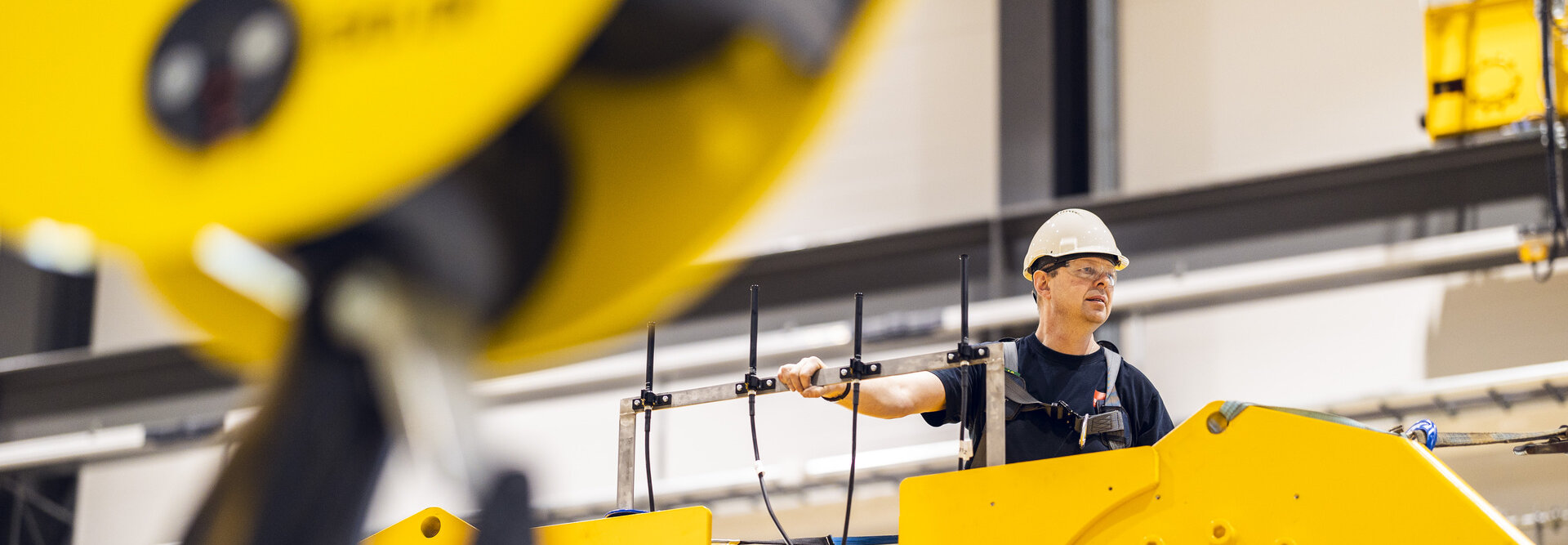 Person on top of a large, yellow hydraulic damper with safety equipment