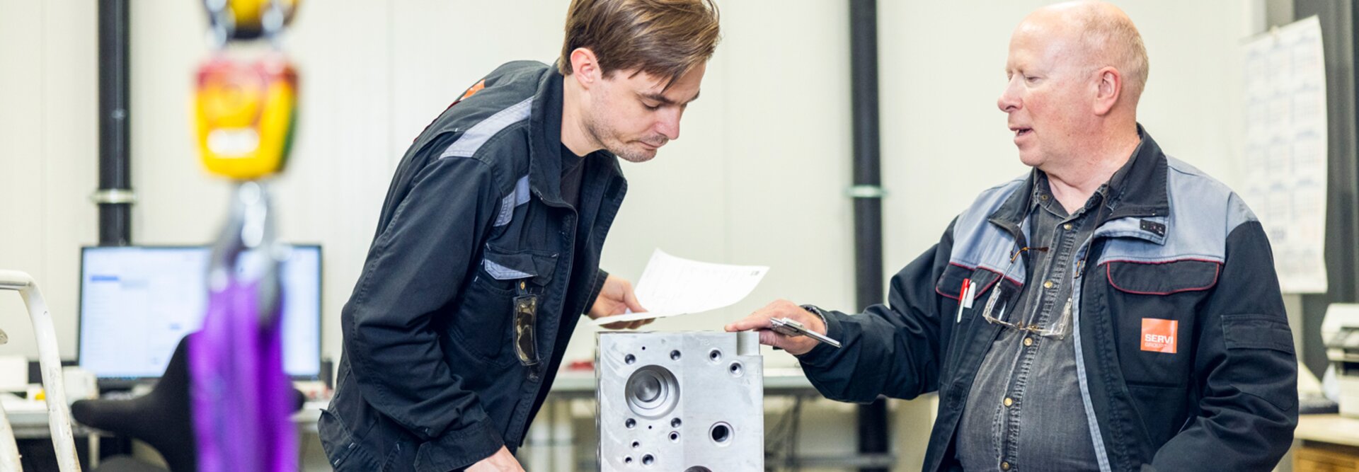 Image of two employees working together to assemble a block, with tools and equipment around them.