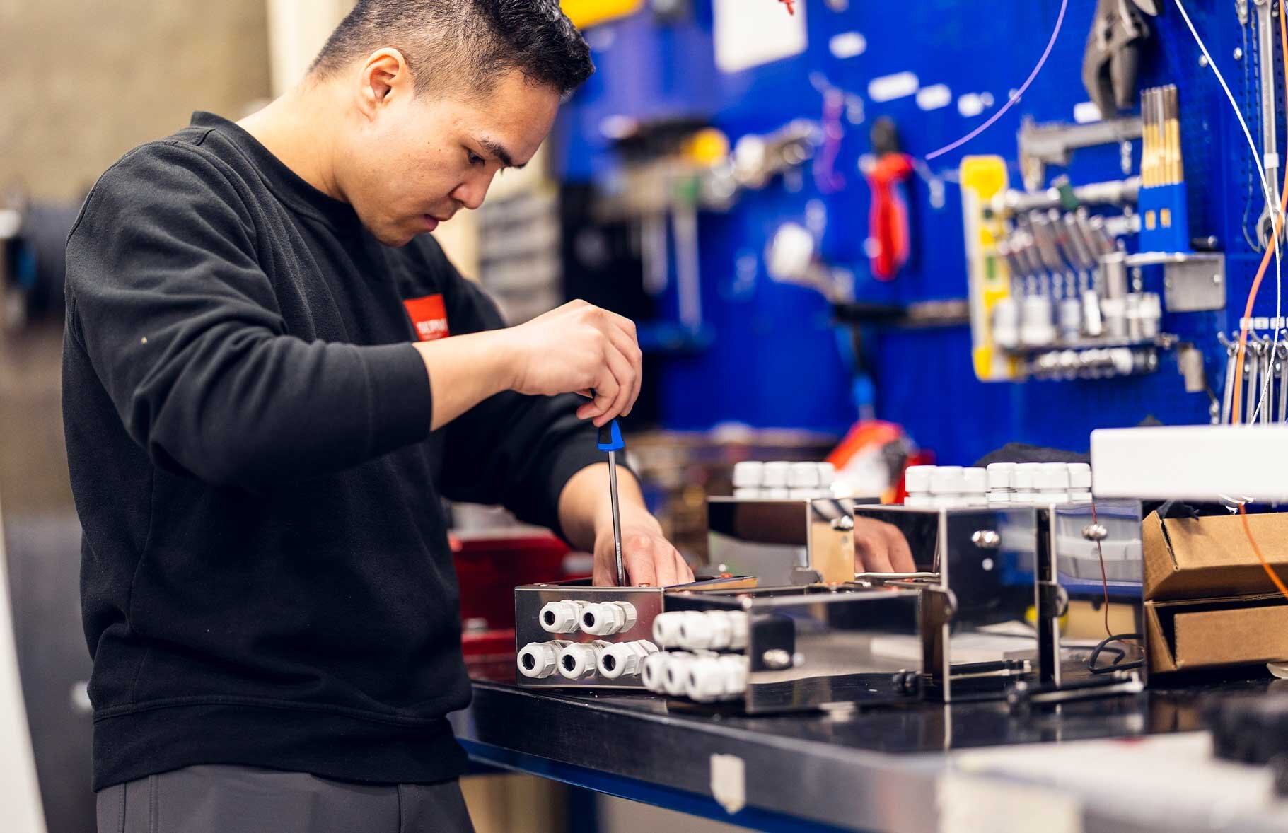 En tekniker fra Servi jobber fokusert med installasjon og finjustering av et elektro- og kontrollsystem i et industrielt miljø. | © Øyvind Welle