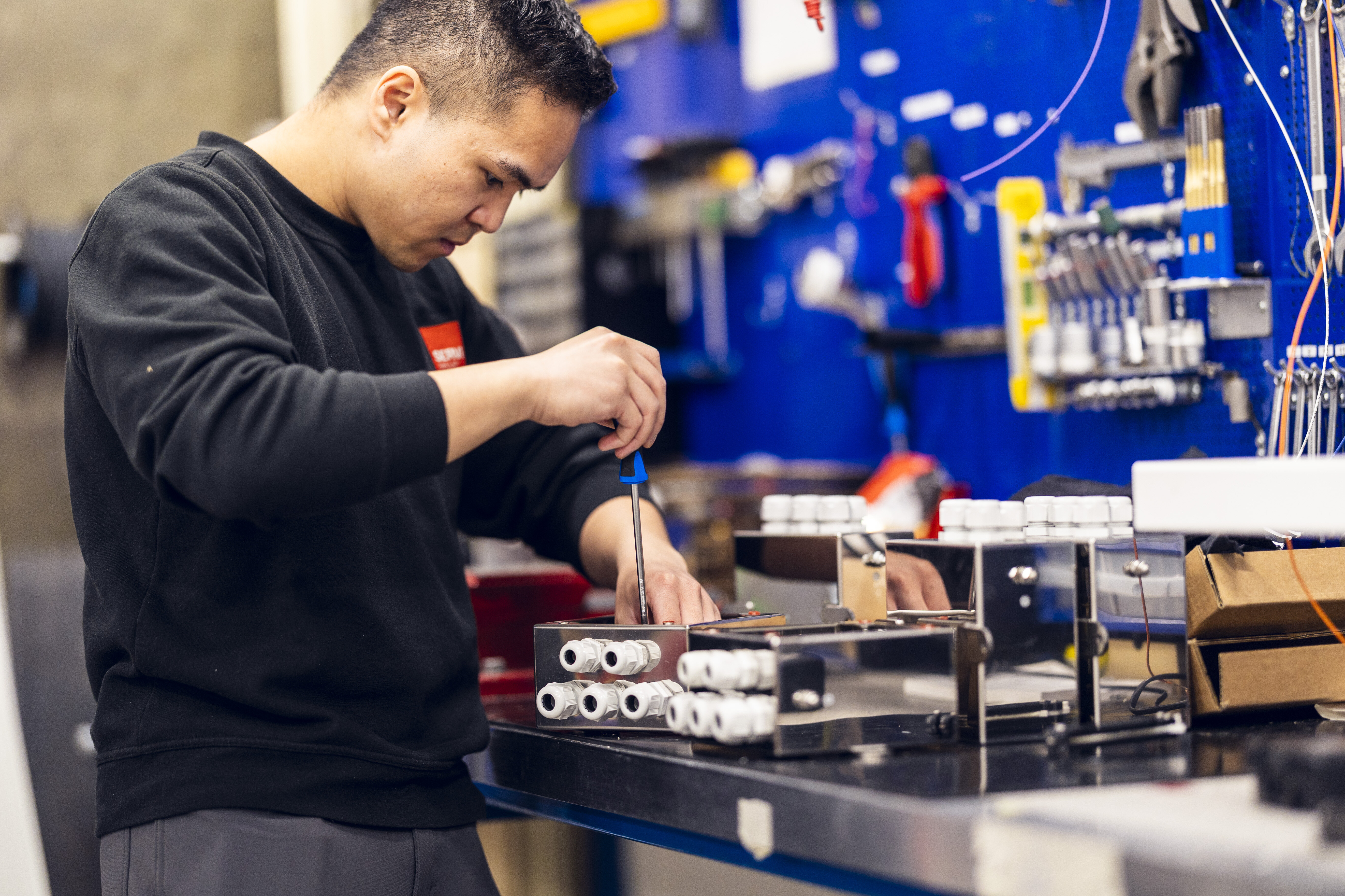 En tekniker fra Servi jobber fokusert med installasjon og finjustering av et elektro- og kontrollsystem i et industrielt miljø. | © Øyvind Welle