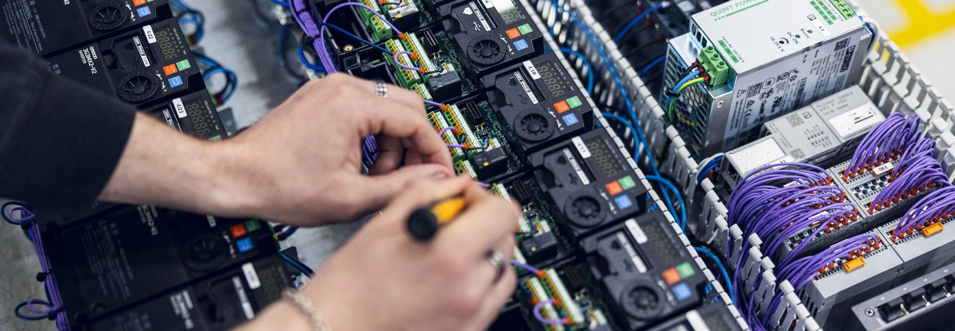 A close-up of technician hands connecting and assembling components inside an electrical cabinet | © Øyvind Welle