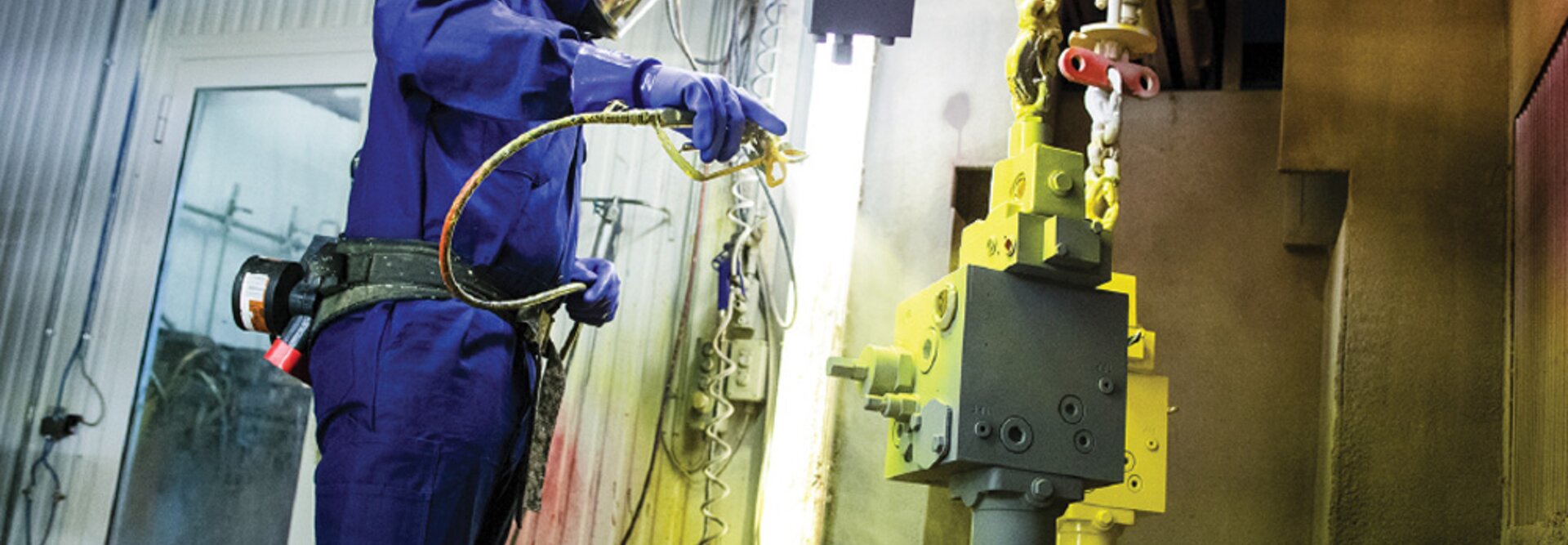 a person does surface treatment on an hydraulic valve with yellow color