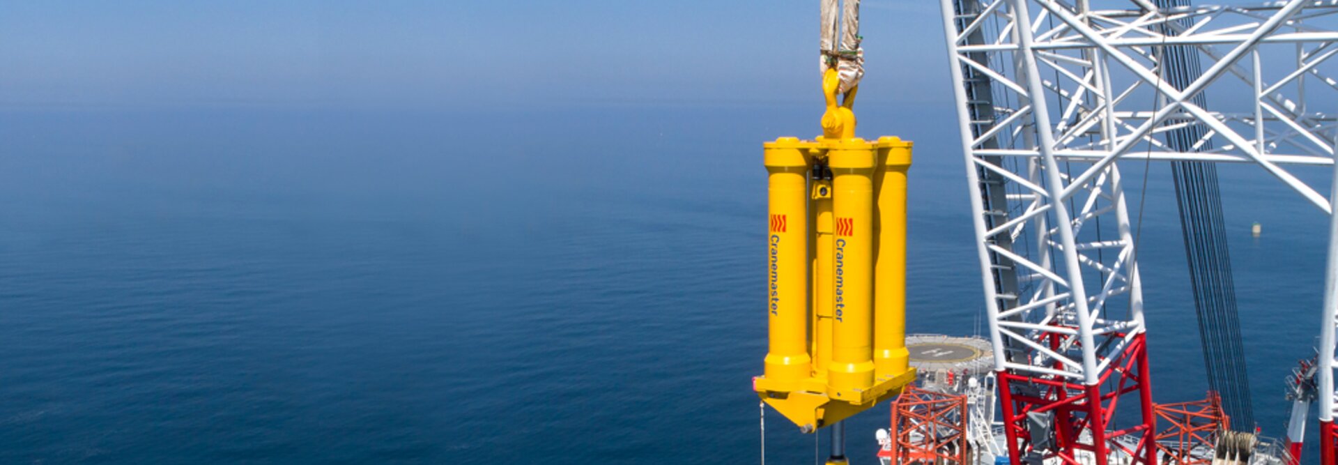 Yellow Cranemaster damper at sea hanging on a offshore wind rig
