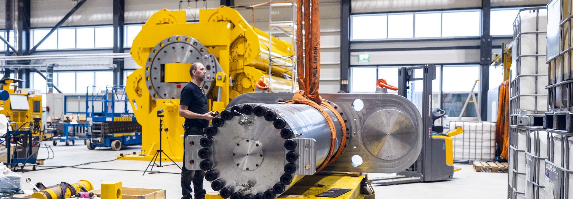Produksjonsmedarbeider heiser 800T sylinder. Hydraulisk demper 300T og stakebil i bakgrunnen  produksjonshall Rissa