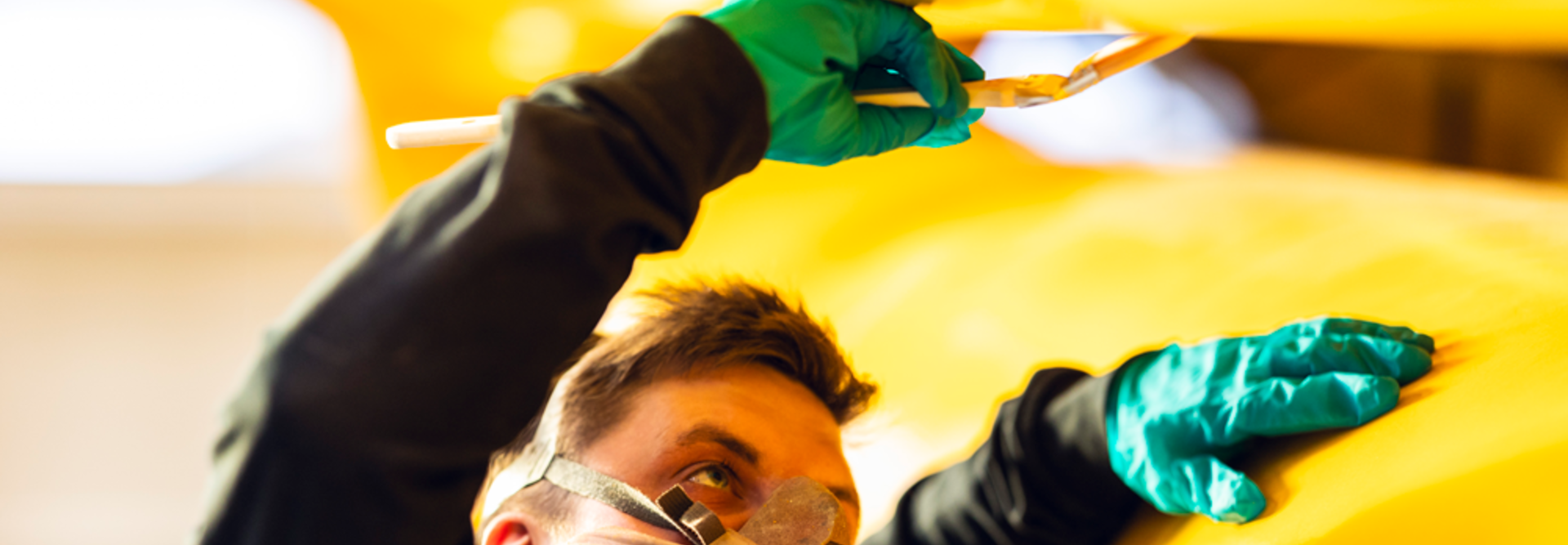 Person wearing mask while smearing yellow paint on a large hydraulic damper