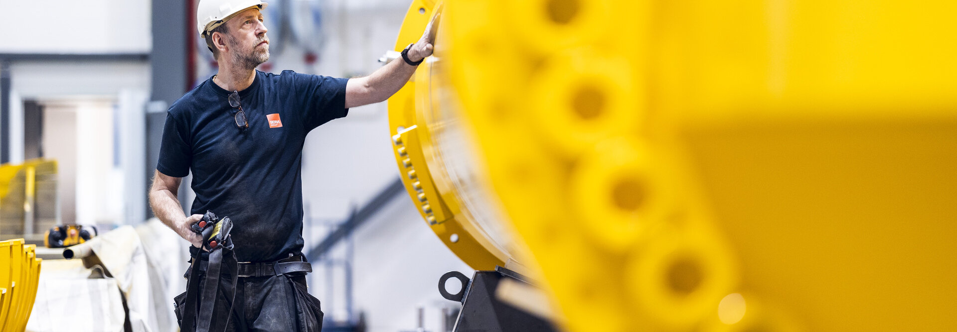 Production worker walks next to yellow cylinder spare part for hydraulic shock absorber 
