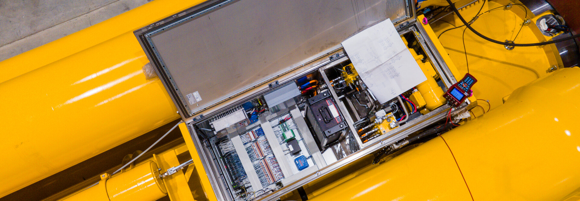 Drone image looking down at an open control cabinet on top of a hydraulic shock absorber 