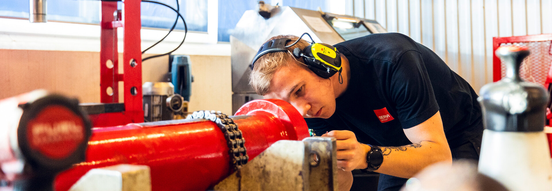 Young service technician works with a red cylinder at the cylinder factory in Rissa