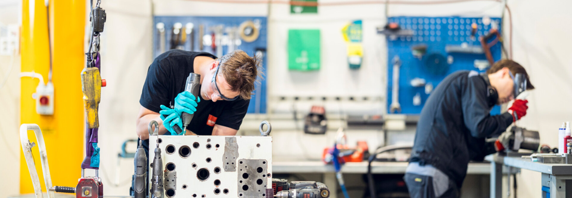 Two person in a workshop overhaling a hydraulic valve